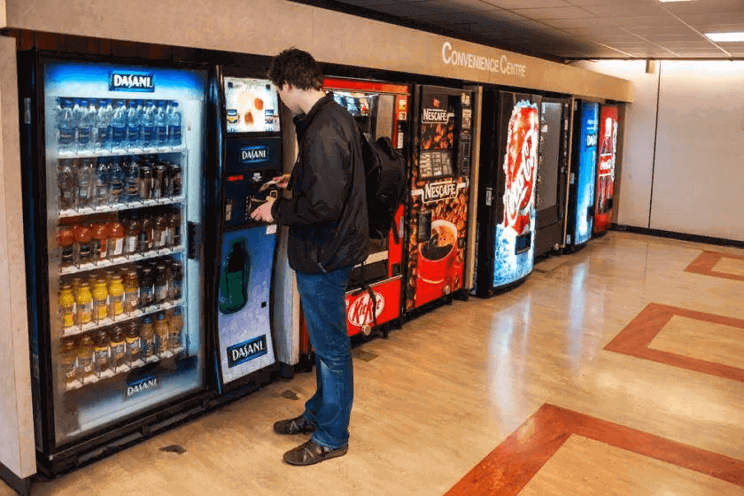 Young man using vending machines in a convenience center.
